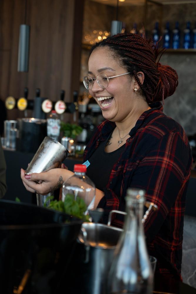 Vrouw shaket een mocktail tijdens een bartenderworkshop voor werkzoekenden